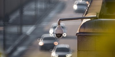 Automatic license plate reader camera mounted on a pole along a Massachusetts road at dusk.
