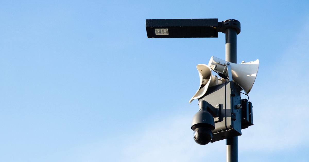 A Flock Safety automatic license plate reader camera mounted on a pole near a suburban street intersection