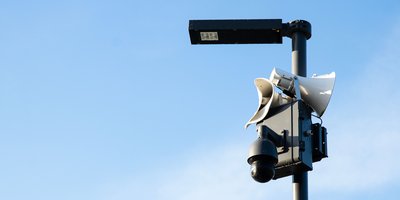 A Flock Safety automatic license plate reader camera mounted on a pole near a suburban street intersection