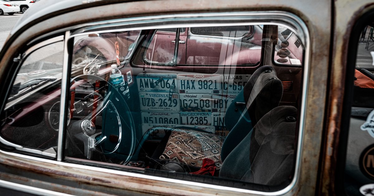 Person performing a FaxVIN license plate lookup on a laptop next to a parked car