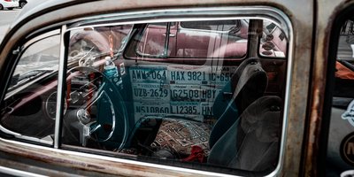 Person performing a FaxVIN license plate lookup on a laptop next to a parked car