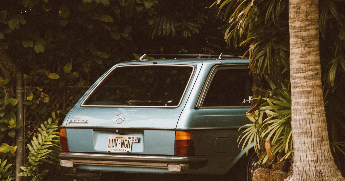 Hawaii license plate lookup showing rainbow design plate on a car driving along an Oahu coastal highway