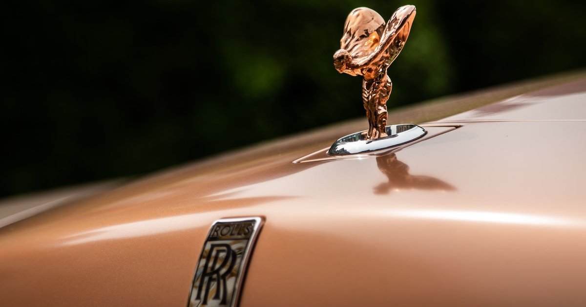 Close-up of a chrome vintage hood ornament on a classic car showing its sculpted design and meaning