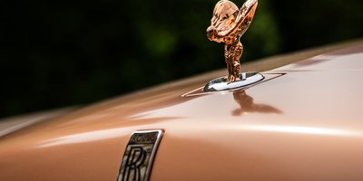 Close-up of a chrome vintage hood ornament on a classic car showing its sculpted design and meaning