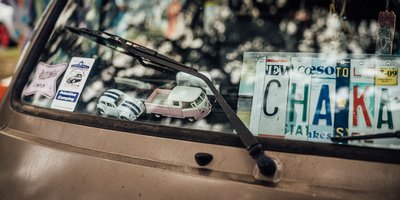 Close-up of a Maine Chickadee vanity plate on a car parked near a coastal lighthouse