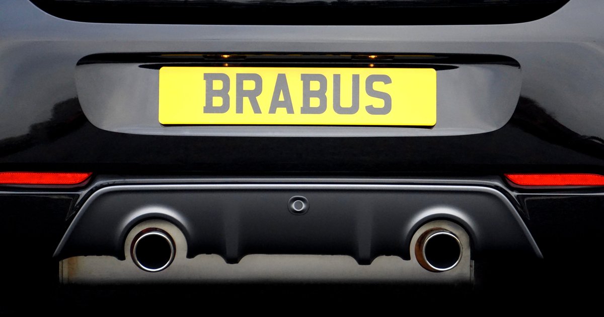Close-up of a car's rear bumper displaying a NERD ALERT vanity plate with playful bumper stickers