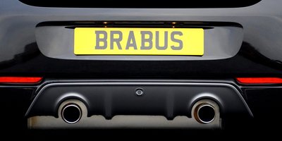 Close-up of a car's rear bumper displaying a NERD ALERT vanity plate with playful bumper stickers
